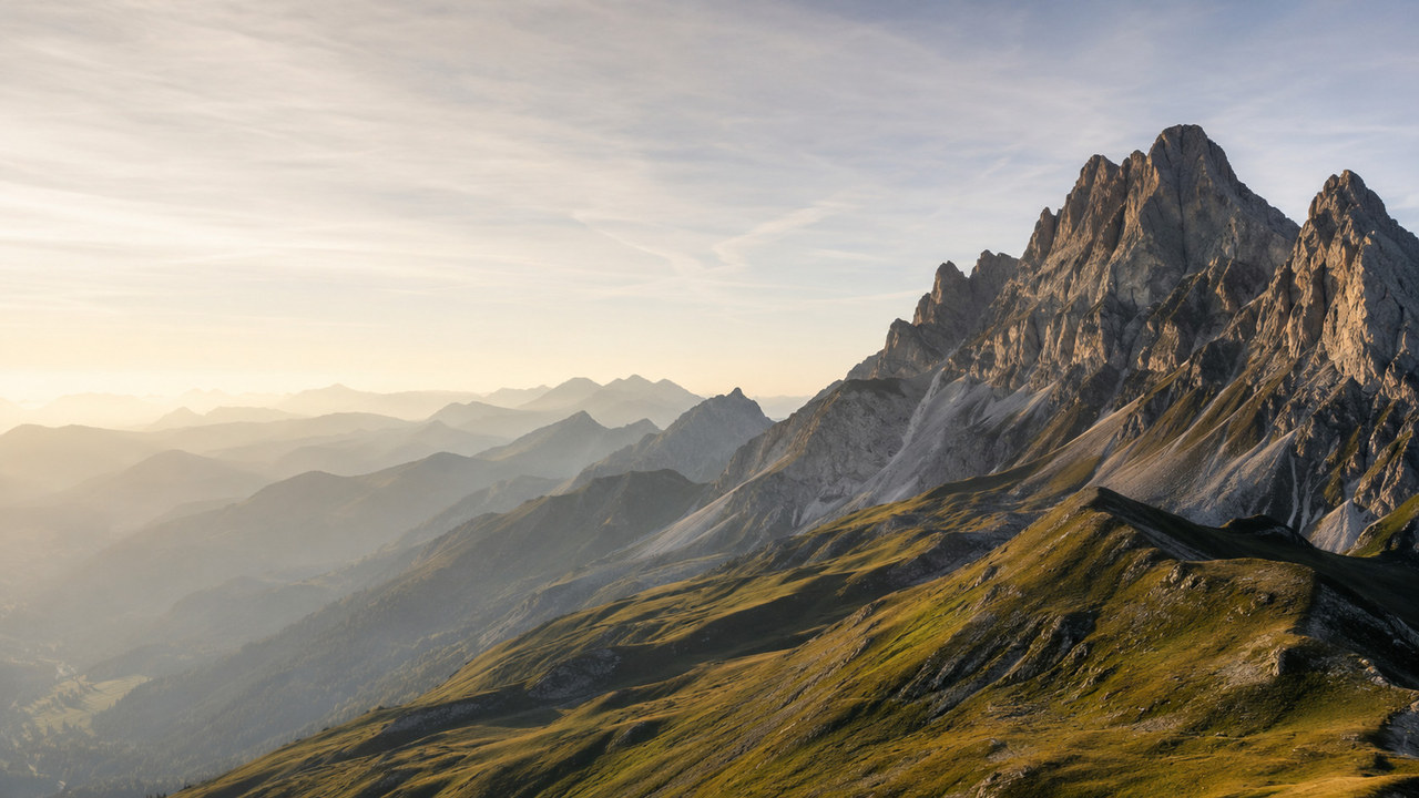 Der Weg zum Gipfel: Unternehmenswert von KMU steigern Felsiges Bergmassiv über grünen Alpweiden im Morgenlicht – Sinnbild für den Aufstieg zu einem höheren Unternehmenswert